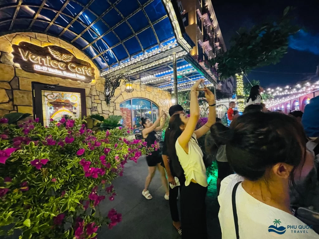 a crowd of people taking picture at venice cafe entrance at sunset town phu quoc